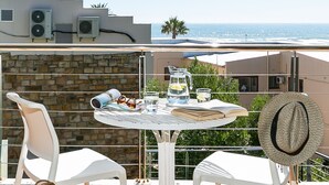 A terrace with a table, two chairs, a hat, and a woven bag.
