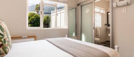 Un dormitorio con cama, ventana, baño y vistas al verdor exterior.