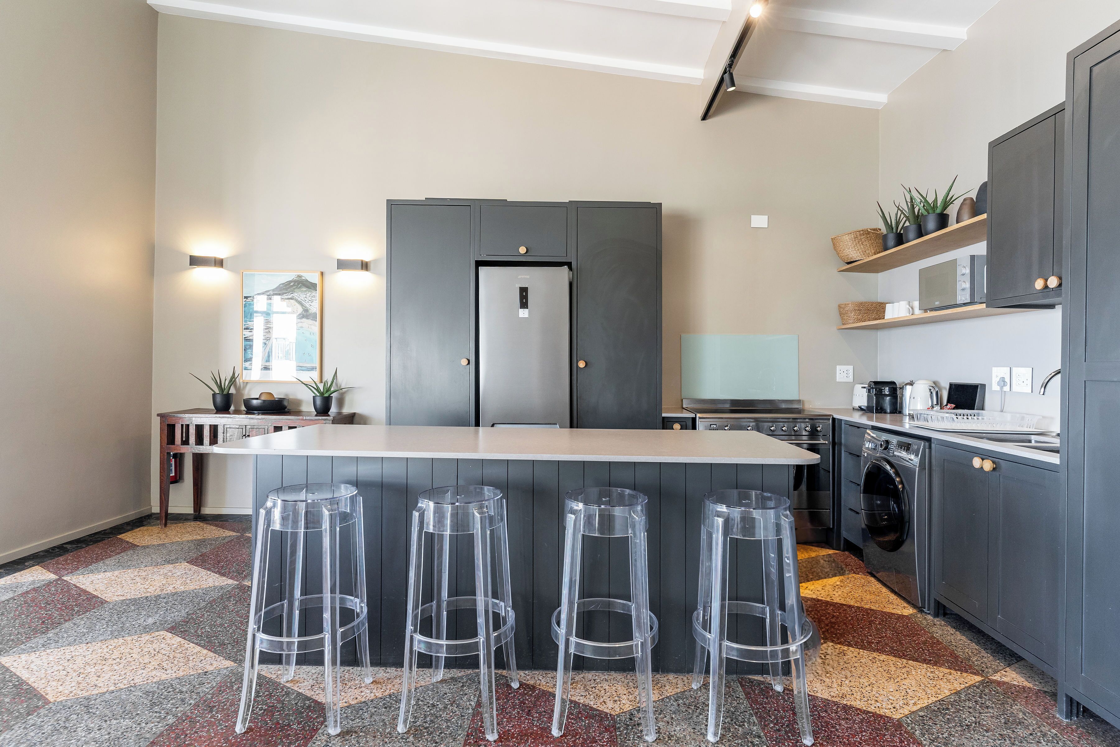 A modern kitchen with a central island, bar stools, a built-in oven, and a microwave.