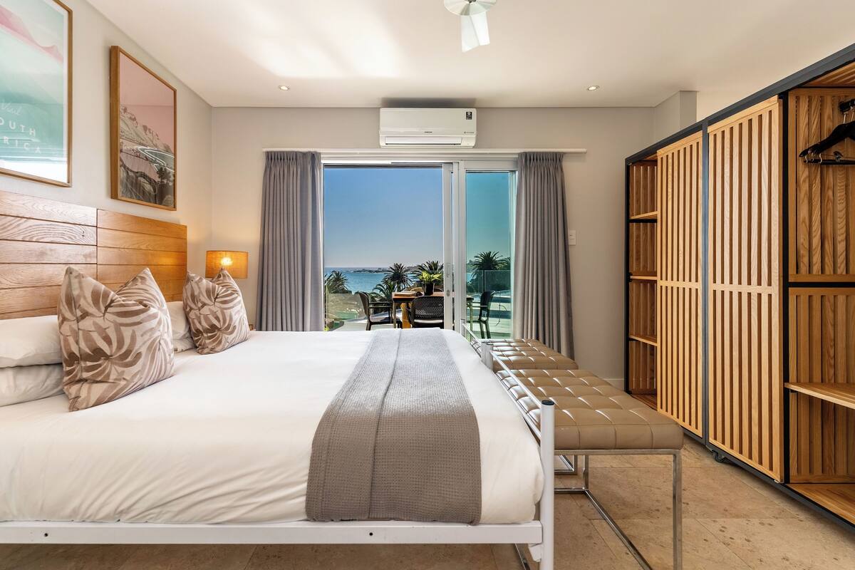 A hotel room with a bed, a balcony with a view, and a wardrobe.