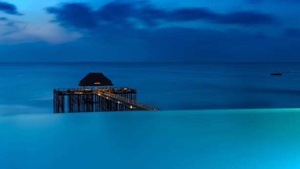 A pier extending into calm waters at twilight with a small structure at the end. - Sea Cliff Resort & Spa (Mangapwani)