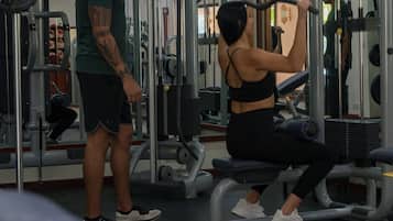 A gym with exercise equipment and a person using a machine.