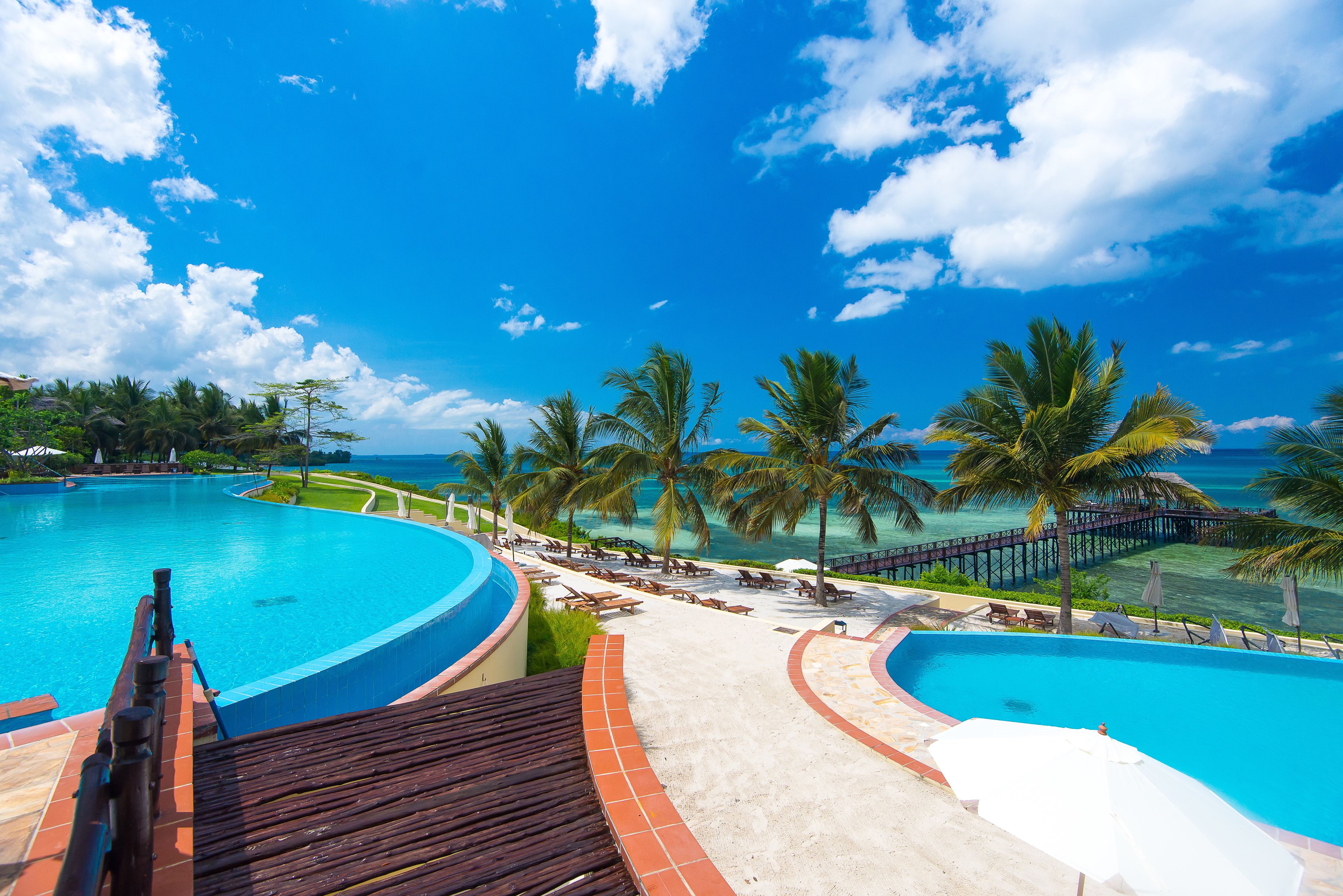 A resort pool area with a clear view of the ocean and a wooden deck.