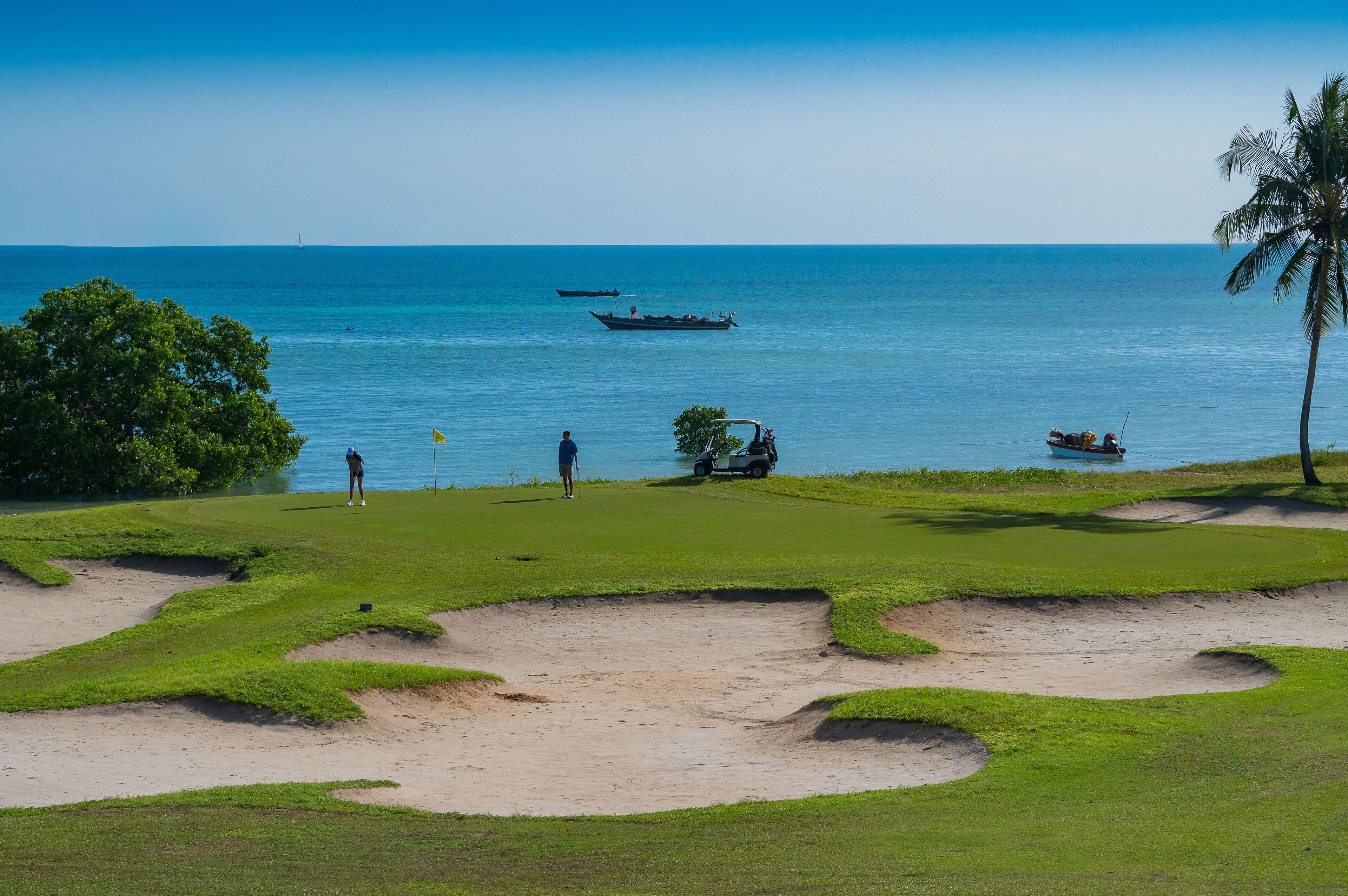 A golf course with bunkers and a view of the ocean.