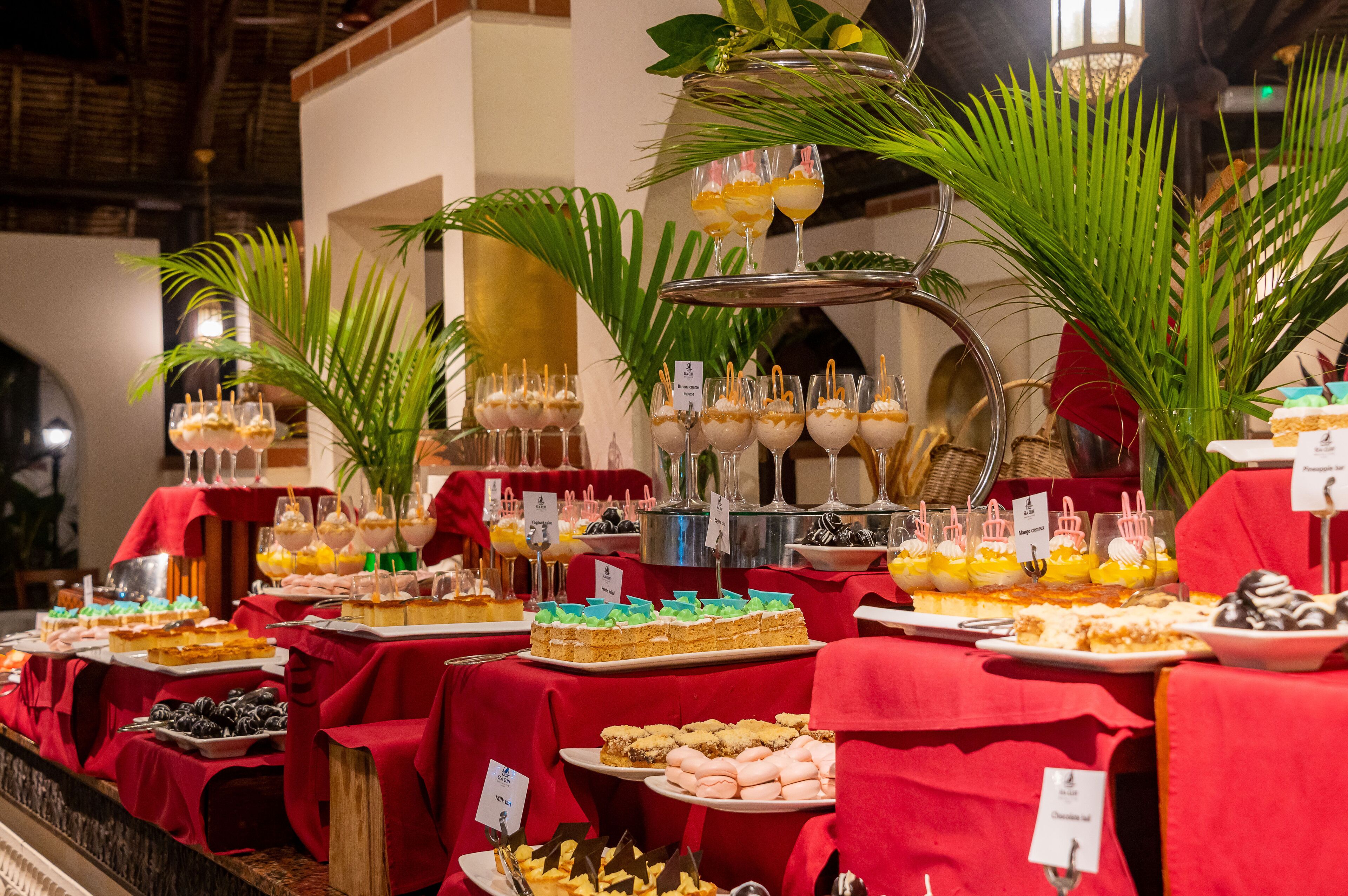 A buffet with various desserts and drinks, including cakes, pastries, and fruit.