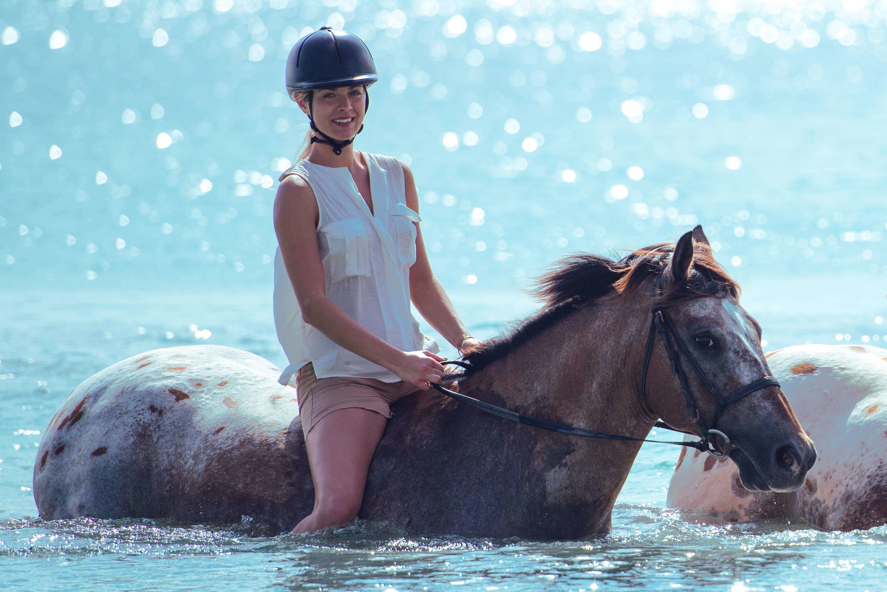 A person riding a horse in a body of water.