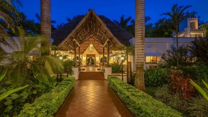 A resort with a thatched-roof structure, a paved pathway, and lush greenery. - Sea Cliff Resort & Spa (Mangapwani)