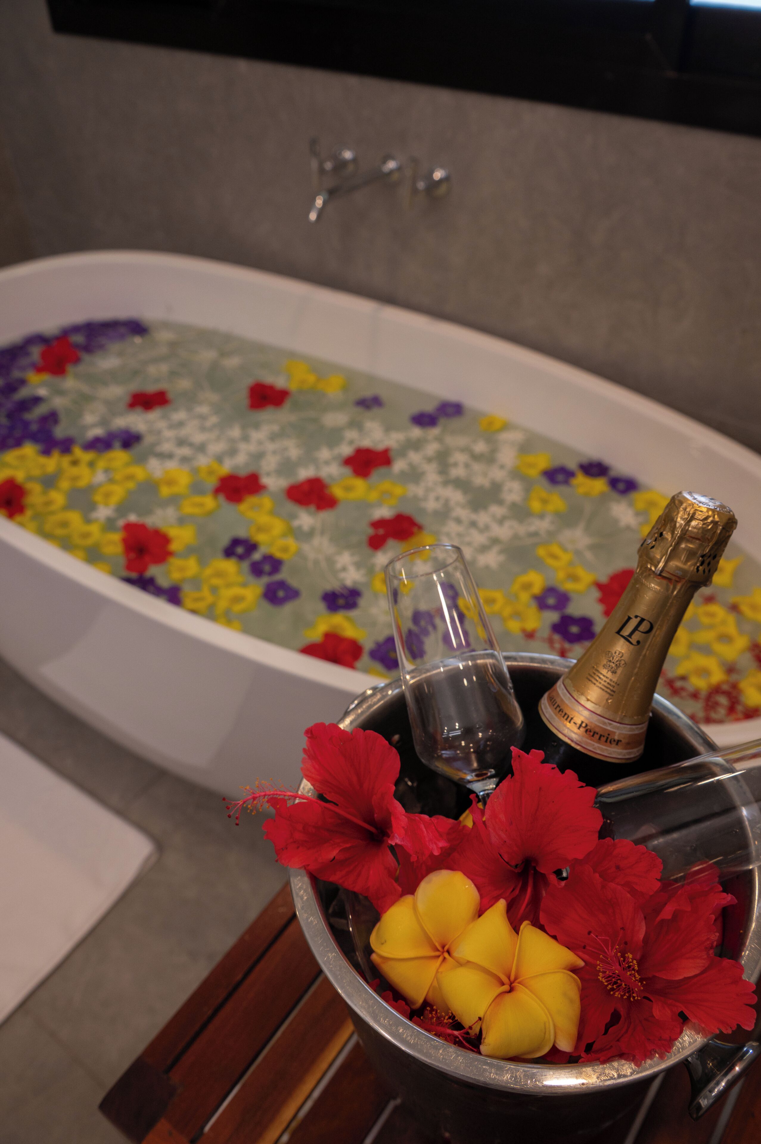 Une baignoire remplie de pastilles effervescentes colorées et une bouteille de champagne.