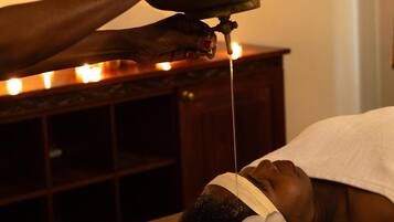 A person receiving a traditional treatment with a metal bowl and a lit candle.