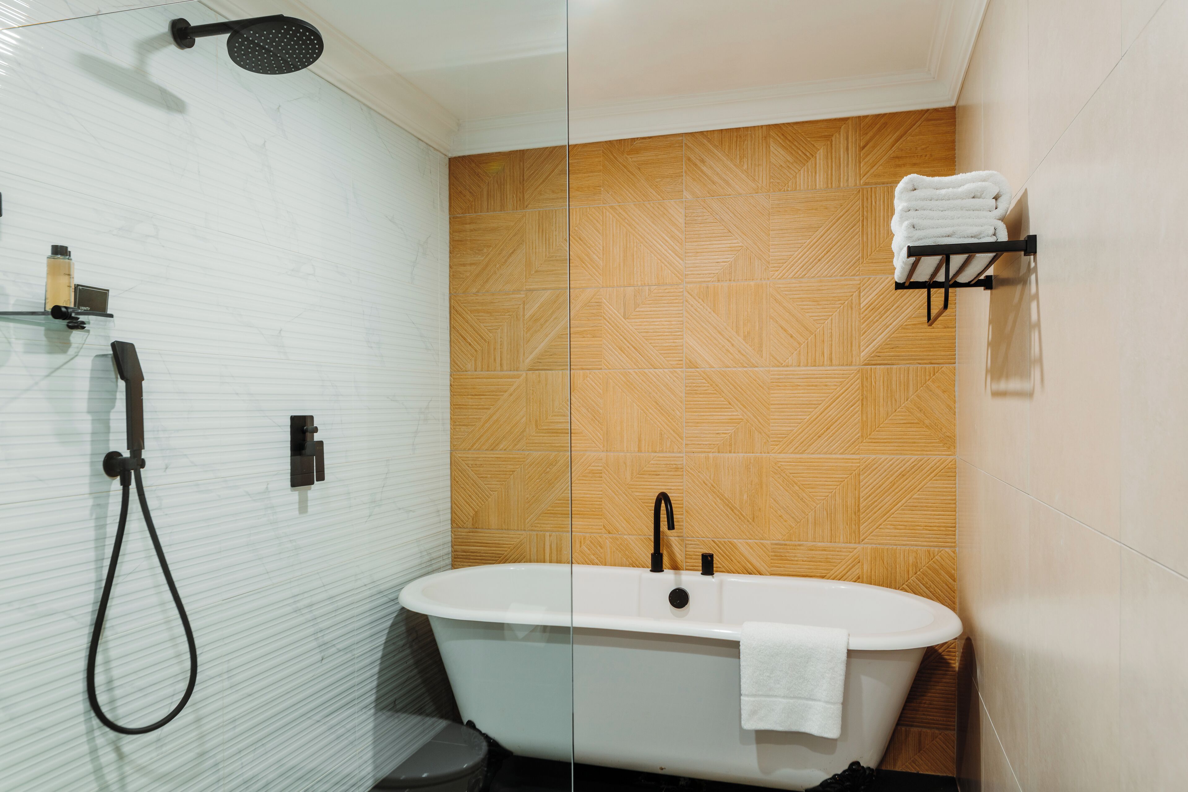 Une salle de bain moderne avec une baignoire sur pieds, une douchette à main et un porte-serviettes fixé au mur.