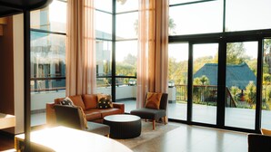 A spacious living area with a large window, a sofa, a chair, and a coffee table. - Emerald Resort & Casino (Vanderbijlpark)