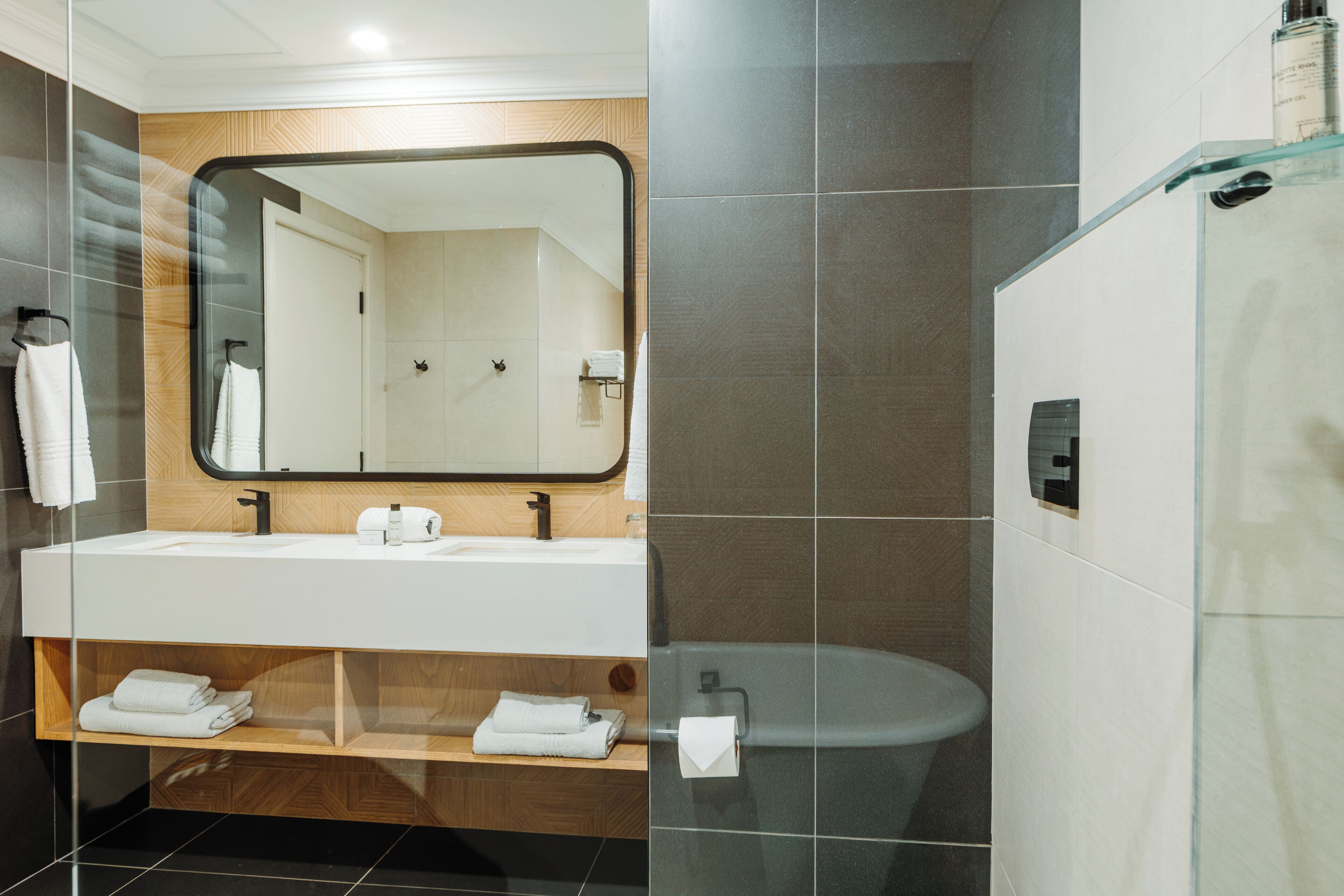 A modern bathroom with a large mirror, white sink, and a glass-enclosed shower area.