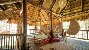 A wooden deck with a thatched roof, a hot tub, and a lounge area with a woven chair and cushions. - Emerald Resort & Casino (Vanderbijlpark)