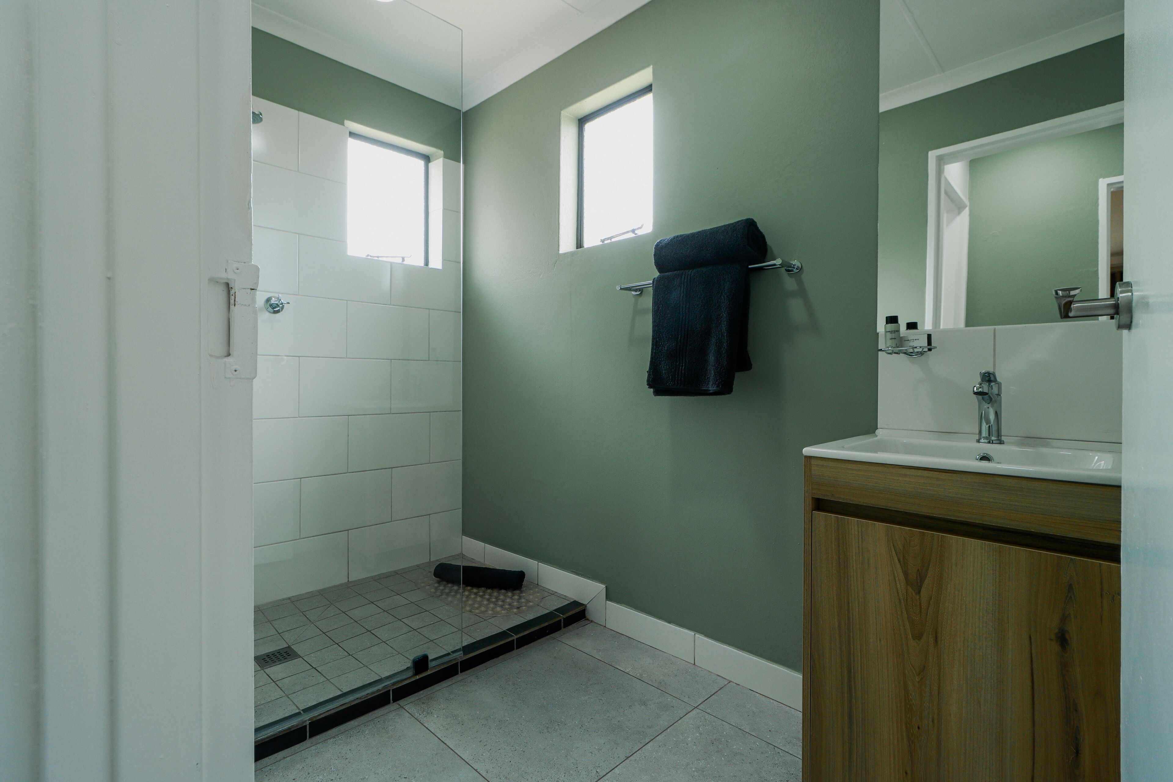 A bathroom with a shower, a sink, and a mirror.