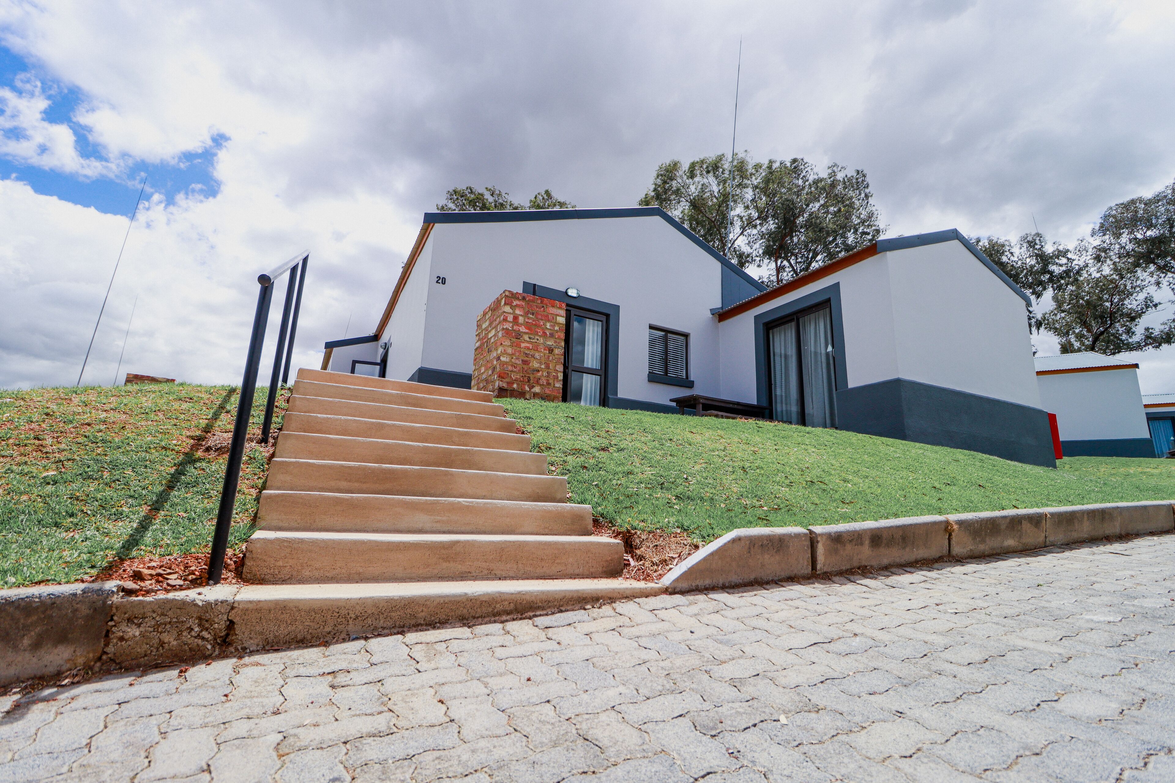 A modern house with a stone staircase leading to the front door, a well-maintained lawn, and a clear sky.