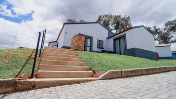 A modern house with a stone staircase leading to the front door, a well-maintained lawn, and a clear sky.