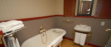 A bathroom with a freestanding bathtub, a vanity with a sink, and a mirror.