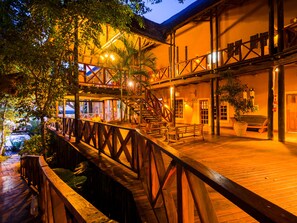 Una terraza de madera con barandilla, una escalera y una zona de estar con bancos.