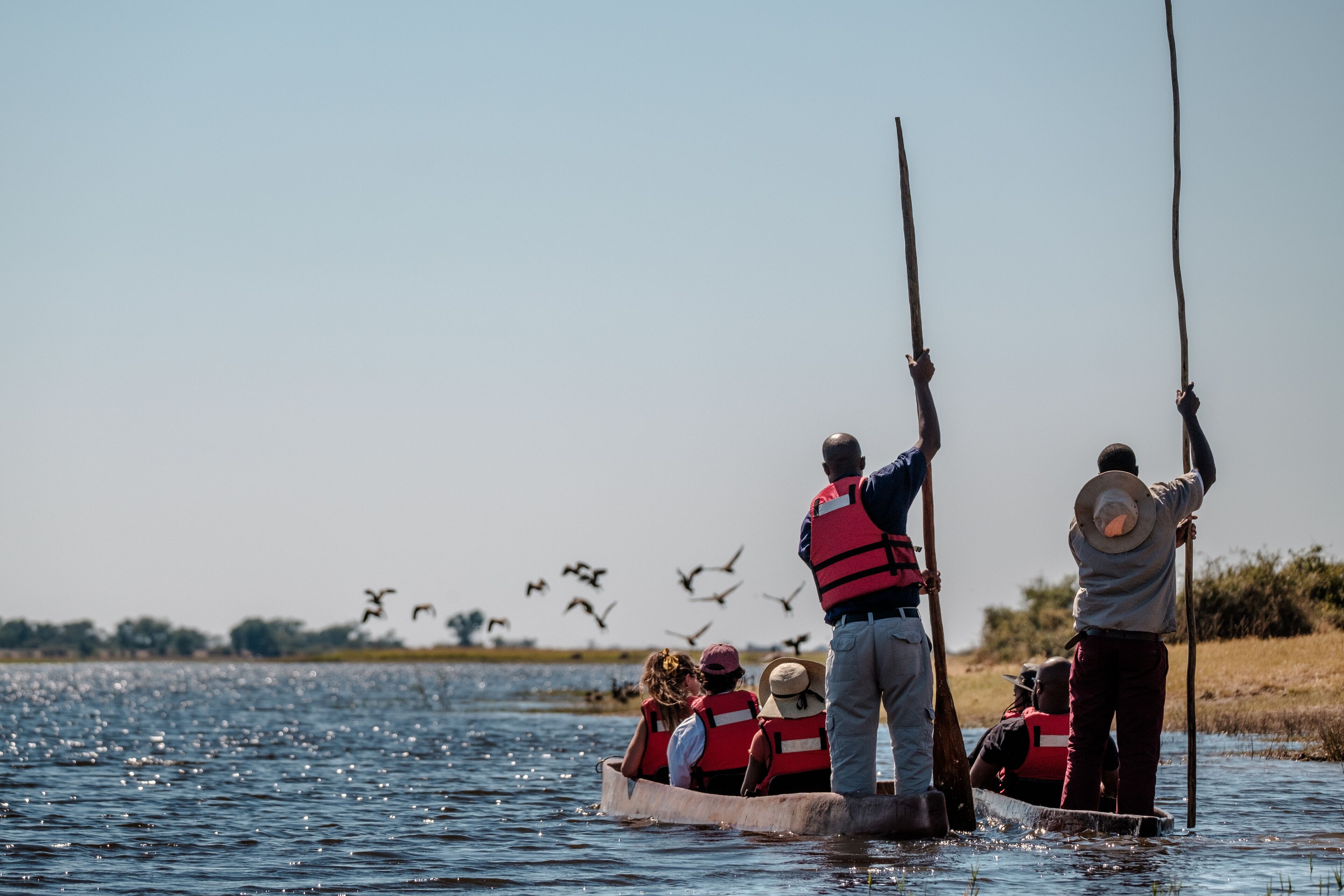 A group of people in a boat on a body of water, wearing life jackets.