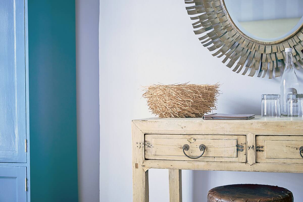 A rustic wooden dresser with a mirror, a glass jar, and a woven basket.