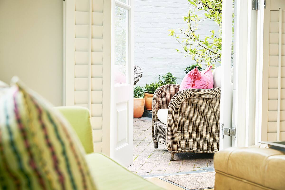 An open doorway leading to a patio area with wicker furniture and potted plants.