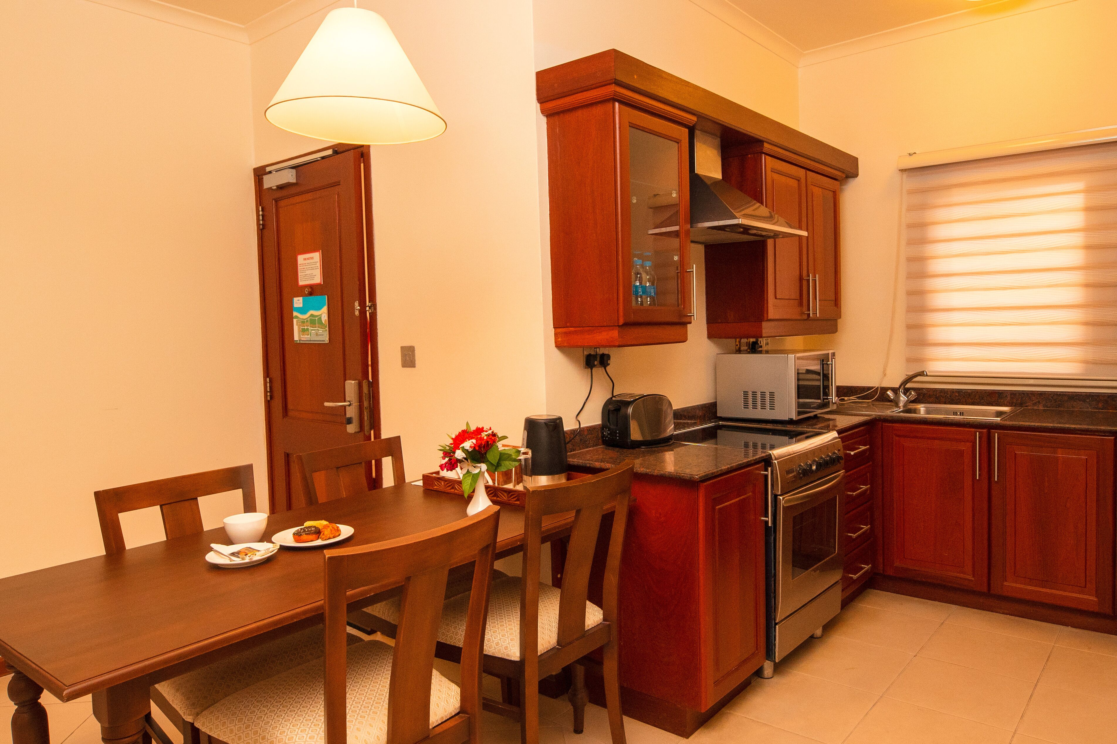 A compact kitchen with wooden cabinets, a microwave, an oven, and a dining table with chairs.