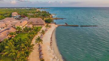 Pantai pribadi, pasir putih, kursi berjemur, dan payung pantai
