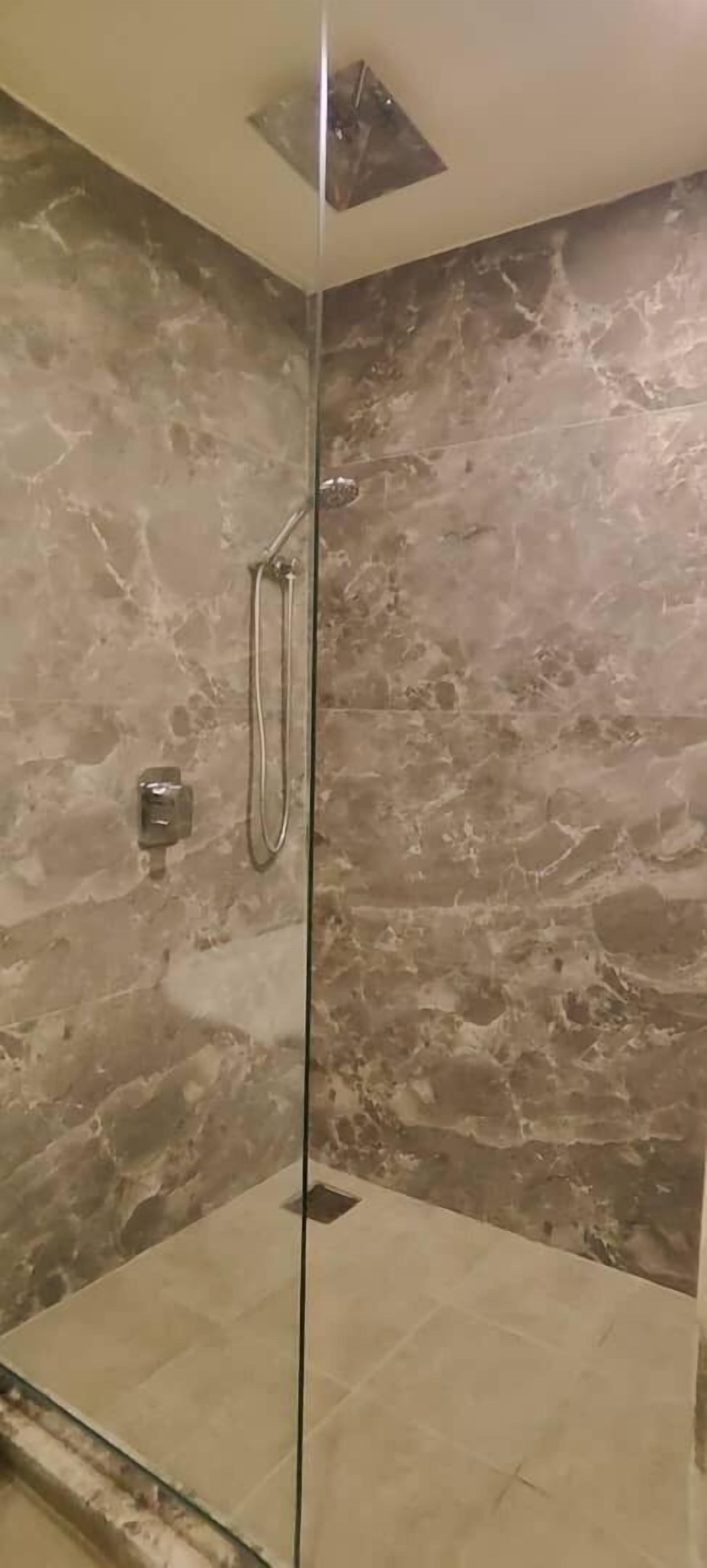 A glass-enclosed shower with a marble wall.