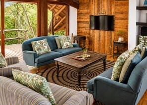 Un espacio acogedor con sofá, sillones, una mesita de centro y un televisor fijado a una pared de madera.