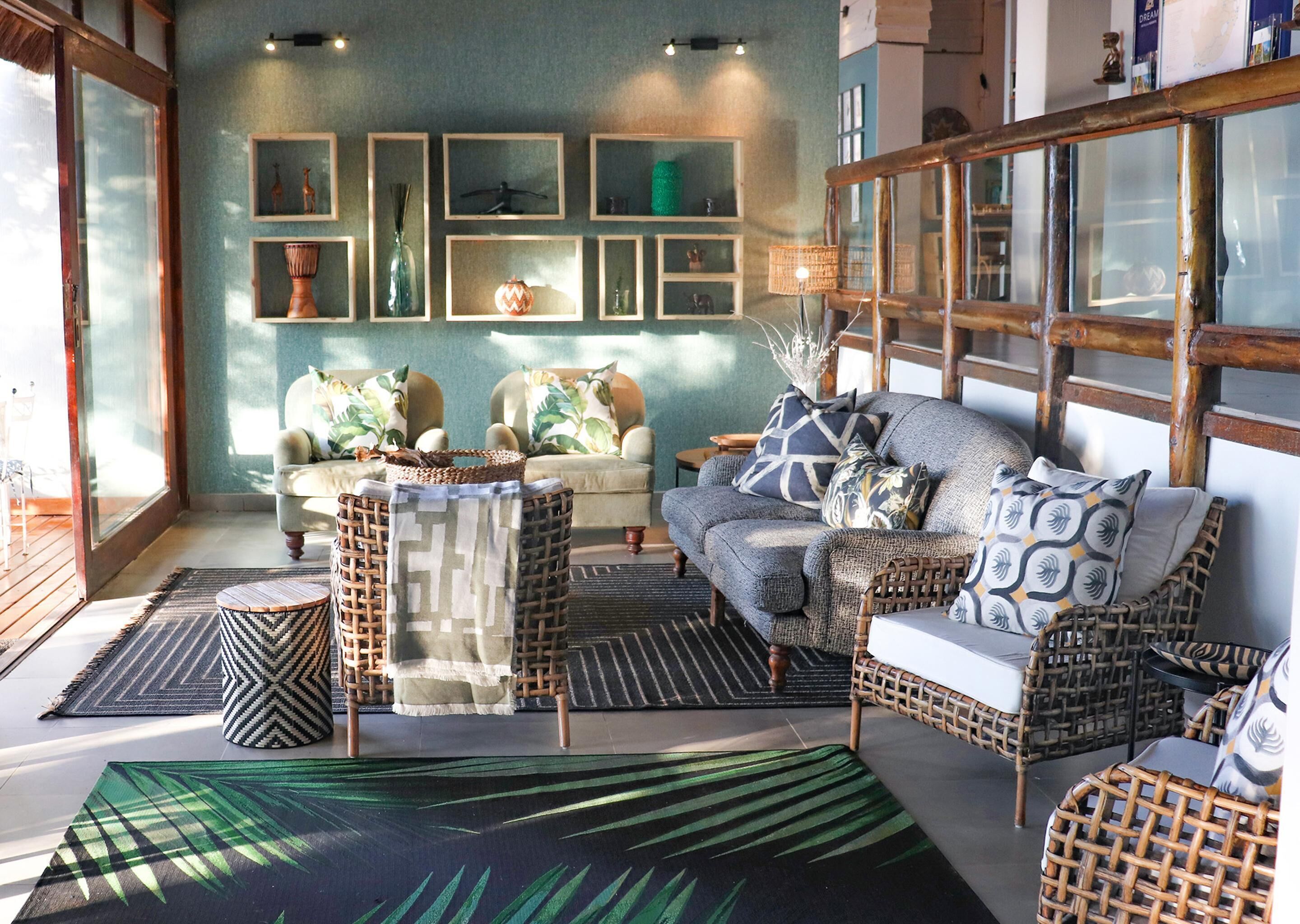 Una sala de estar acogedora con muebles de mimbre, un sofá con cojines estampados y una pared decorada con elementos enmarcados.