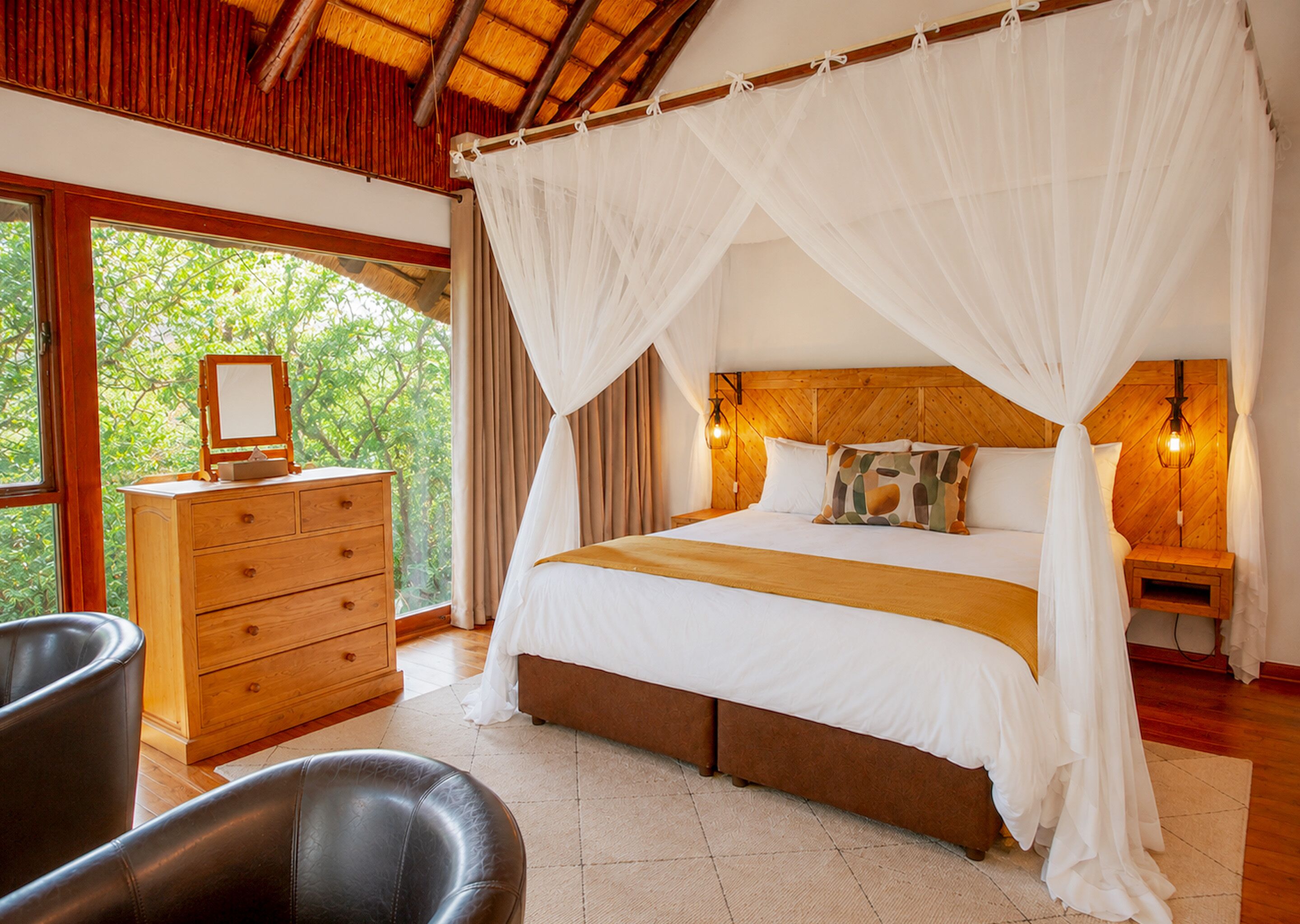 Quarto com cama, cómoda de madeira e mesa de cabeceira com abajur.