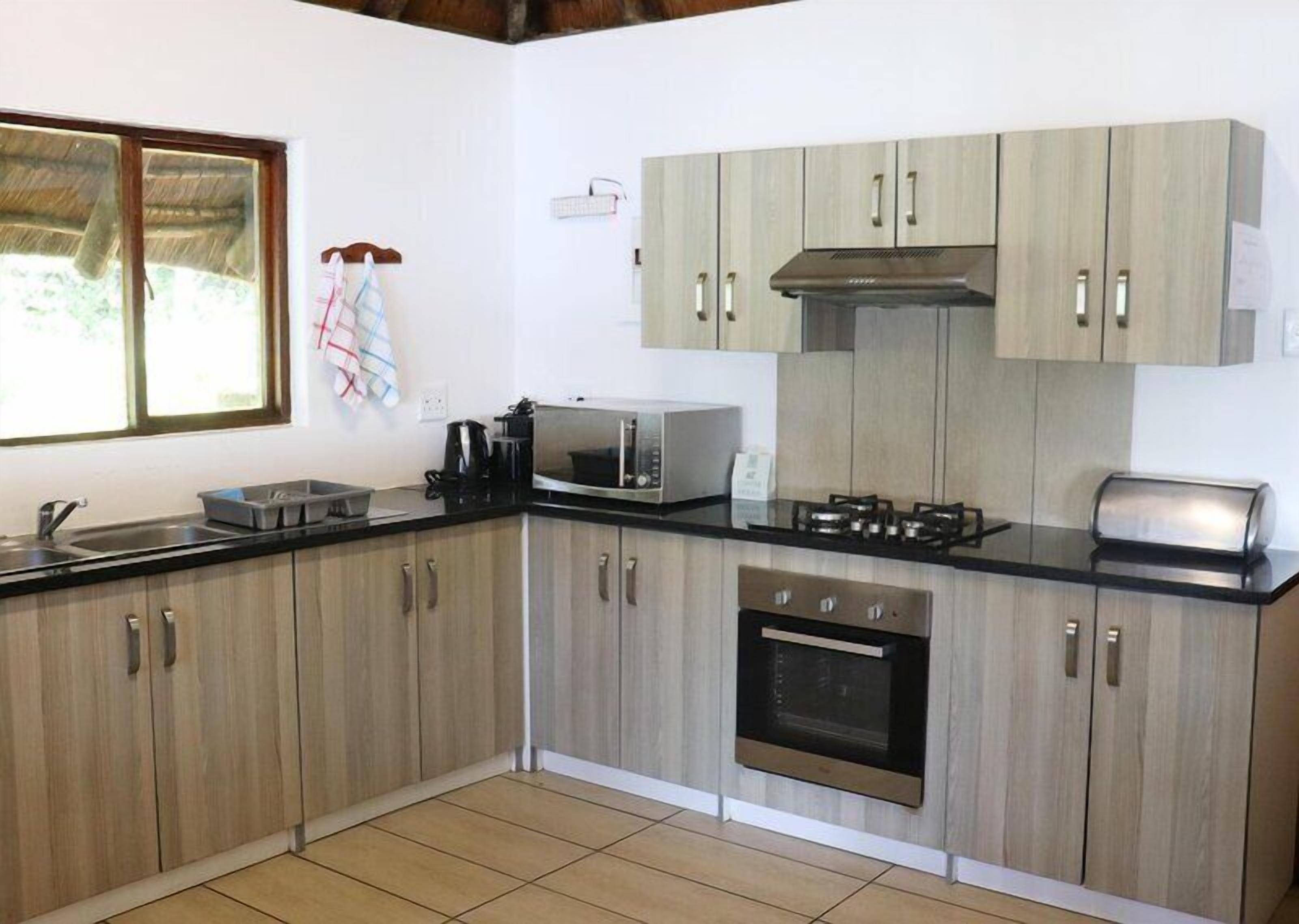 Una cocina con armarios de madera, microondas, estufa a gas y tostadora.