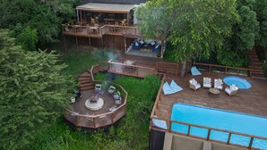Une terrasse extérieure à plusieurs niveaux avec une piscine, entourée d’une végétation luxuriante.