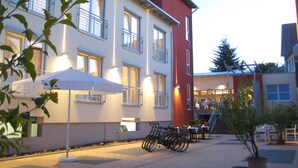 A building with multiple windows, a red section, and outdoor seating with umbrellas. - Ringhotel Bundschu (Bad Mergentheim)