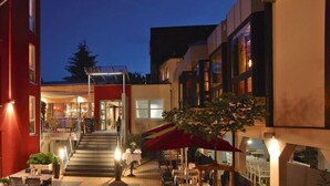 A hotel courtyard with outdoor seating, a staircase leading to the entrance, and a red awning. - Ringhotel Bundschu (Bad Mergentheim)