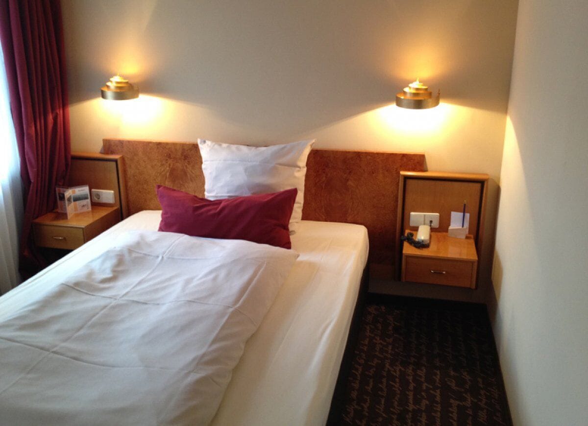 A hotel room with a large bed, two bedside tables, and a headboard.