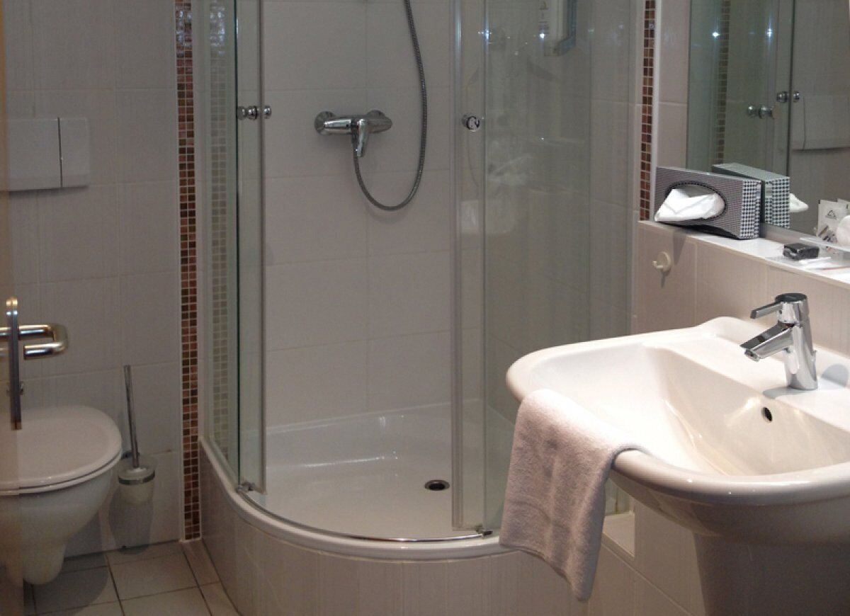 A modern bathroom with a glass-enclosed shower, a white sink, and a toilet.