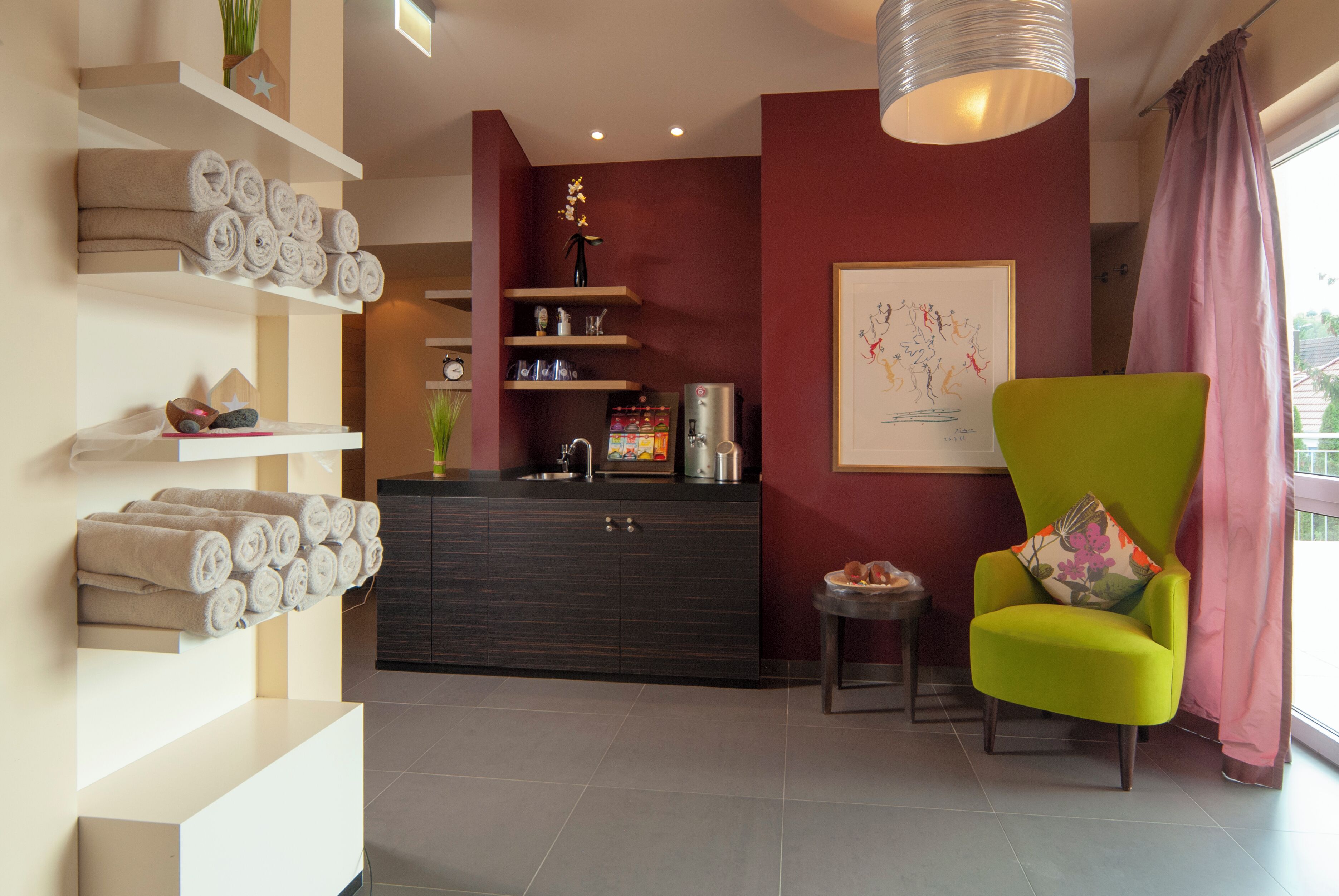 A modern bathroom with a vanity, towel racks, and a green armchair.
