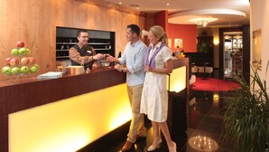 A reception desk with a wooden finish, a chandelier, and a red carpet. - Ringhotel Bundschu (Bad Mergentheim)