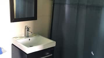 A bathroom with a white sink, dark cabinetry, a mirror, and a blue shower curtain.
