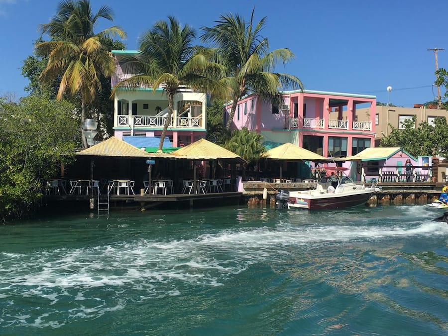A waterfront property with a dock, a boat, and a building with a balcony.