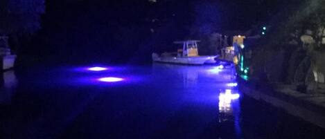 A nighttime view of a river with boats and a dock.