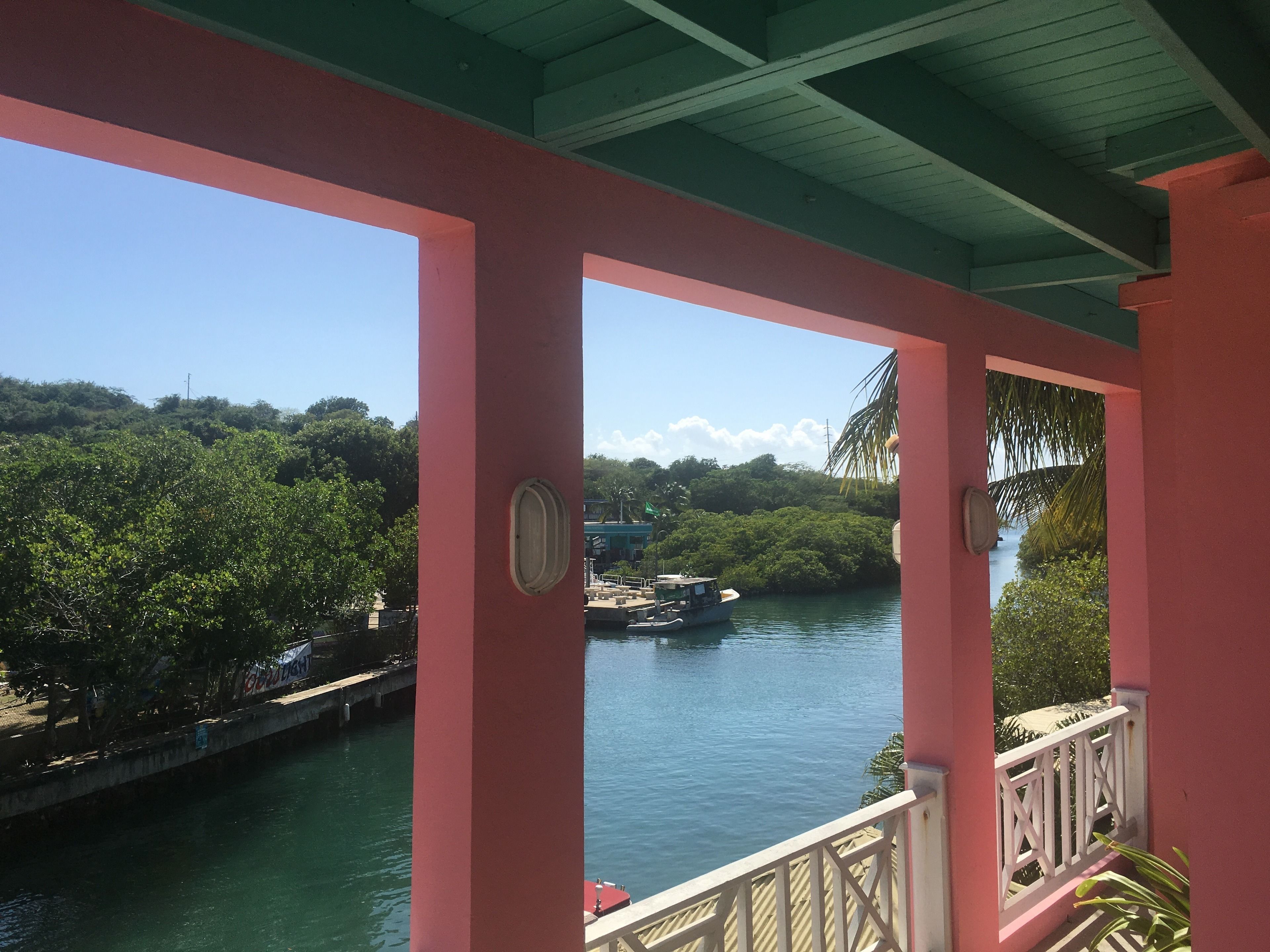 Un bâtiment rose doté d’un balcon donnant sur une rivière.