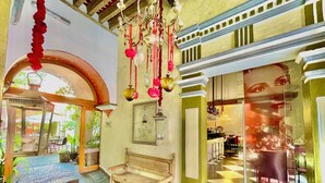 A cozy interior with a wooden bench, a hanging red lantern, and a glass-fronted shop displaying various items. - El Sueño Hotel & Spa (Puebla)