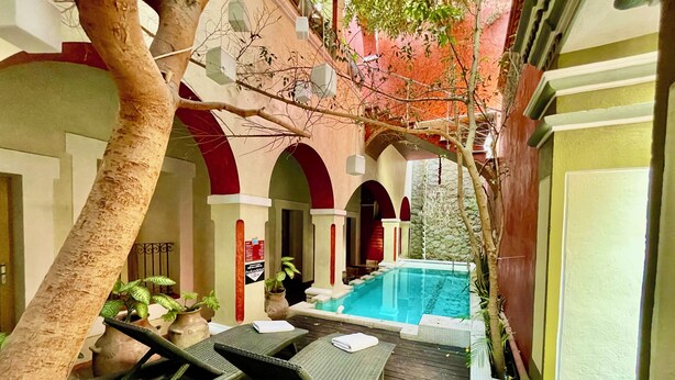 A pool area with lounge chairs, a small waterfall, and a stone wall. - El Sueño Hotel & Spa (Puebla)
