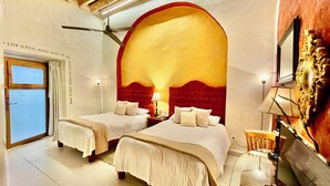 A hotel room with two beds, a large arched window, and a ceiling fan. - El Sueño Hotel & Spa (Puebla)