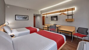 Hotellihuone, jossa on kaksi sänkyä, työpöytä, tuoli, televisio ja naulakko.