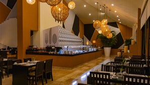 A modern restaurant with a central bar, multiple dining tables, and hanging spherical light fixtures. - Smart Cancun The Urban Oasis (Cancun)