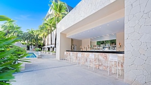A bar area with a pool and palm trees in the background. - Smart Cancun The Urban Oasis (Cancun)