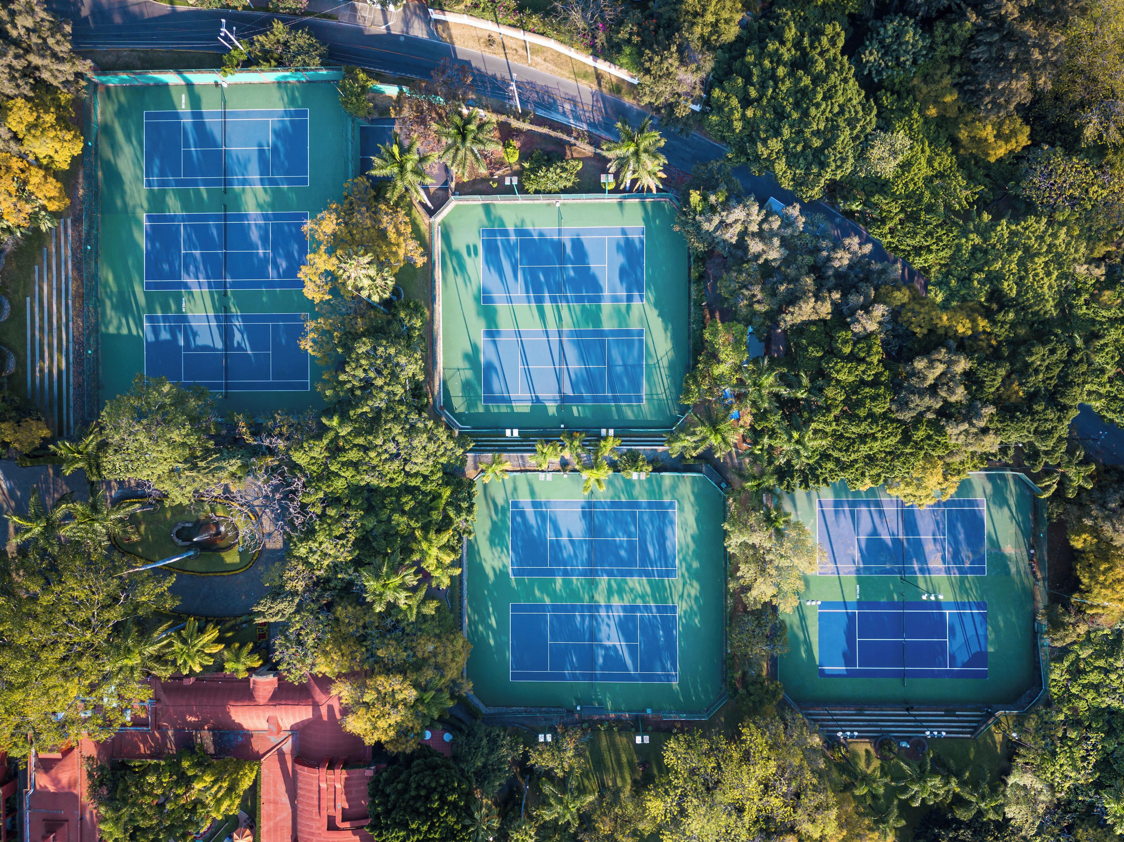 An aerial view of a tennis court complex surrounded by trees.